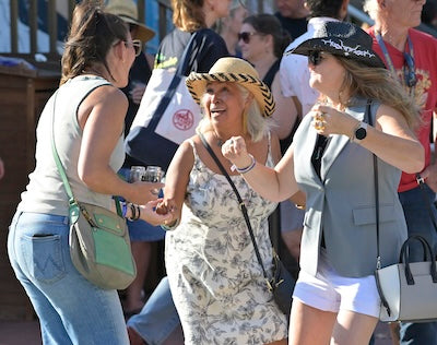 Three women interacting outdoors, with one giving a thumbs-up gesture.