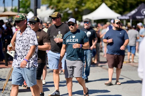 People walking outdoors with one person wearing a 'I ❤️ BEER' shirt.